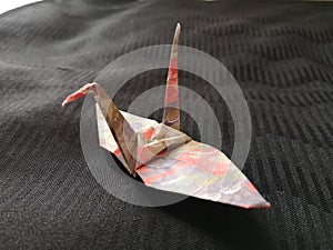 Closeup shot of an origami bird on a black textile