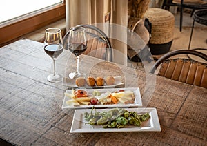 Closeup shot of Padron peppers, Plateau Fromage, and Arancini balls served with two wine glasses