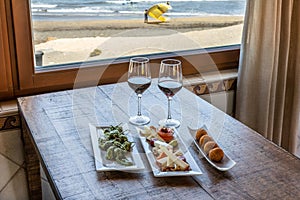 Closeup shot of Padron peppers, Plateau Fromage, and Arancini balls served with two wine glasses