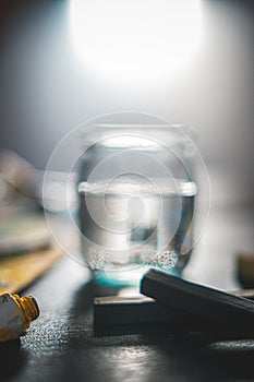 Closeup shot of a painting colour board near a color tube and a water glass bank