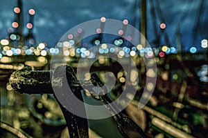 Closeup shot of part of a rusty railing in a city at night with bokeh lights in the background