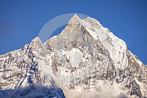 Closeup shot of the peak of the Machapuchare mountain in Nepal with a blue sky in the background