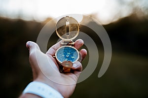 Closeup shot of a person holding a compass with a blurred background photo