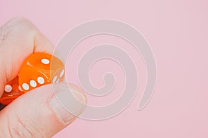 Closeup shot of a person holding a dice over a pink surface