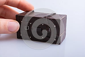 Closeup shot of a person holding a mini old leather suitcase isolated on a grey background