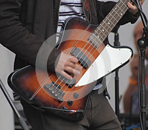 Closeup shot of a person playing the bass guitar on the stage during a concert