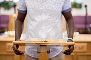 Closeup shot of a person reading the bible on a wooden stand in the church