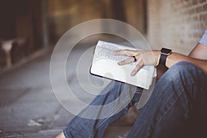 Closeup shot of a person sitting down on the ground and reading the bible with blurred background