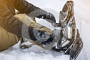 Closeup shot of a person tieing up her snowboard in the snow
