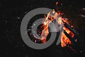 Closeup shot of a person warming his hands on a campfire at night - perfect for wallpapers