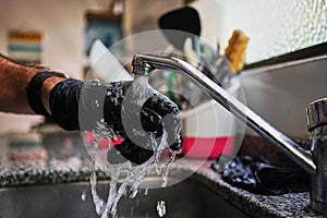 Closeup shot of a person washing hands in the sink in the kitchen