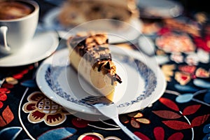Closeup shot of a piece of cake on dish on a floral table cloth