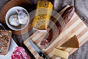 Closeup shot of a piece of parmesan cheese Ventricina sausage and bread on a cutting board