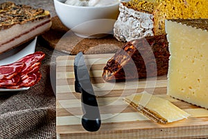 Closeup shot of a piece of parmesan cheese Ventricina sausage and bread on a cutting board