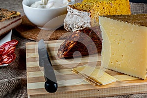 Closeup shot of a piece of parmesan cheese Ventricina sausage and bread on a cutting board