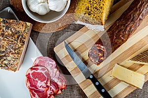 Closeup shot of a piece of parmesan cheese Ventricina sausage and bread on a cutting board