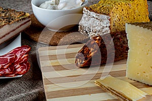Closeup shot of a piece of parmesan cheese Ventricina sausage and bread on a cutting board