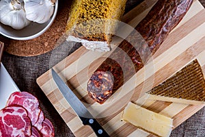 Closeup shot of a piece of parmesan cheese Ventricina sausage and bread on a cutting board