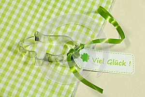 Closeup shot of a pig shaped cookie cutter, a green ribbon, and tag with text good luck in german photo