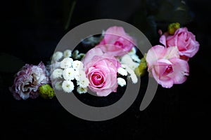 Closeup shot of pink roses and white chrysanthemum flowers on a dark background