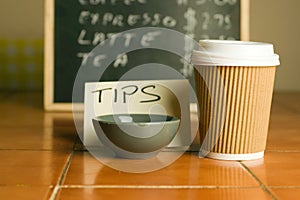 Closeup shot of plastic coffee cup and bowl for tips with a pricelist background