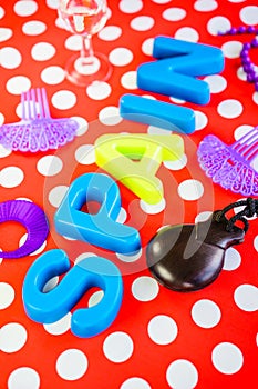 Closeup shot plastic letters spelling [SPAIN}  purple ornaments castanets on red dotted background