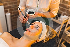 closeup shot of a pretty young woman getting mask on her face at the beauty center, facial treatment