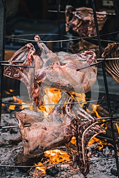 Closeup shot of raw lamb ribs on a traditional circular grill, being cooked with fire