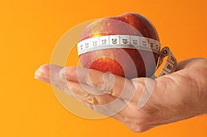 Closeup shot of a red apple with measuring centimetric tape on the hand photo