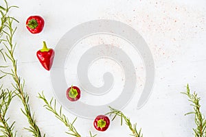 Closeup shot of red chilly peppers and raw rosemary branches on a white background