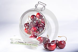 Closeup shot of red, juicy cherries in a glass jar on a white background