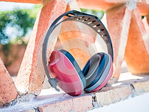 Closeup shot of red noise canceling construction headphones leaning on a patterned structure photo