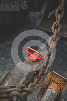 Closeup shot of a red Oval Master Lifting Ring on grunge metal surface with old metal chain