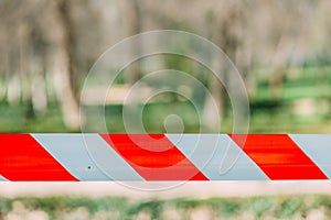 Closeup shot of a red and white barricade tape in the park