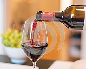 Closeup shot of a red wine pouring from a bottle to a glass