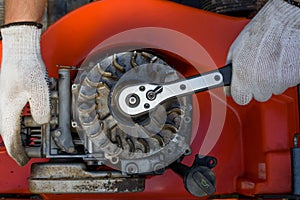 Closeup shot of a repairman fixing an old petrol lawnmower