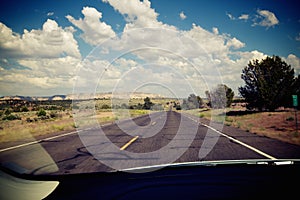 Closeup shot of the road surrounded by trees seen through the car windshield in Utah