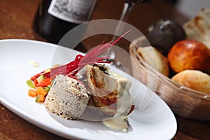 Closeup shot of roast chicken served with risotto and fresh vegetables on a white plate