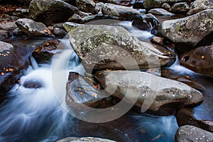 Closeup shot of the rocks in the cascading flow of the river on a cold day
