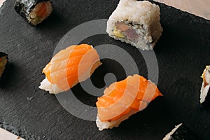 Closeup shot of rolled and cut delicious salmon and rice sushis on a black board