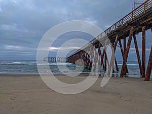 Closeup shot of Rosarito Pier along the sand and sea on a cloudy day in Mexico photo