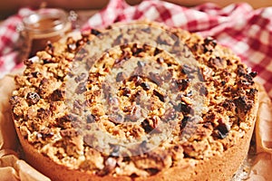 Closeup shot of a round apple pie topped with crumble and roasted nuts, on a towel