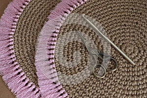 Closeup shot of round brown knit placemats with pink tassels