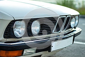 Closeup shot of the round headlights of a white vintage classic car