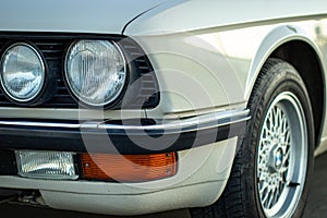 Closeup shot of the round headlights of a white vintage classic car