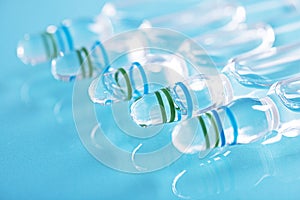 Closeup shot of a row of closed glass vials with clear liquid on a blue surface