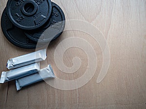 Closeup shot of rubberized discs and fitness bars on a wooden background