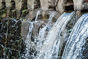 Closeup shot of rushing water flowing off a brick wall