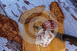 Closeup shot of salami cut on wooden table with fresh bread with cereals