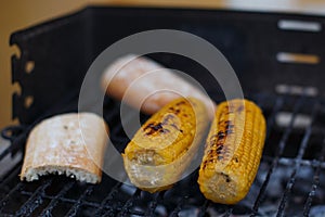 Closeup shot of salted corn grilled next to bread on the grates outdoors